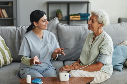 Professionnelle de santé accompagnant une personne âgée à domicile : futur modèle des Maisons France Autonomie